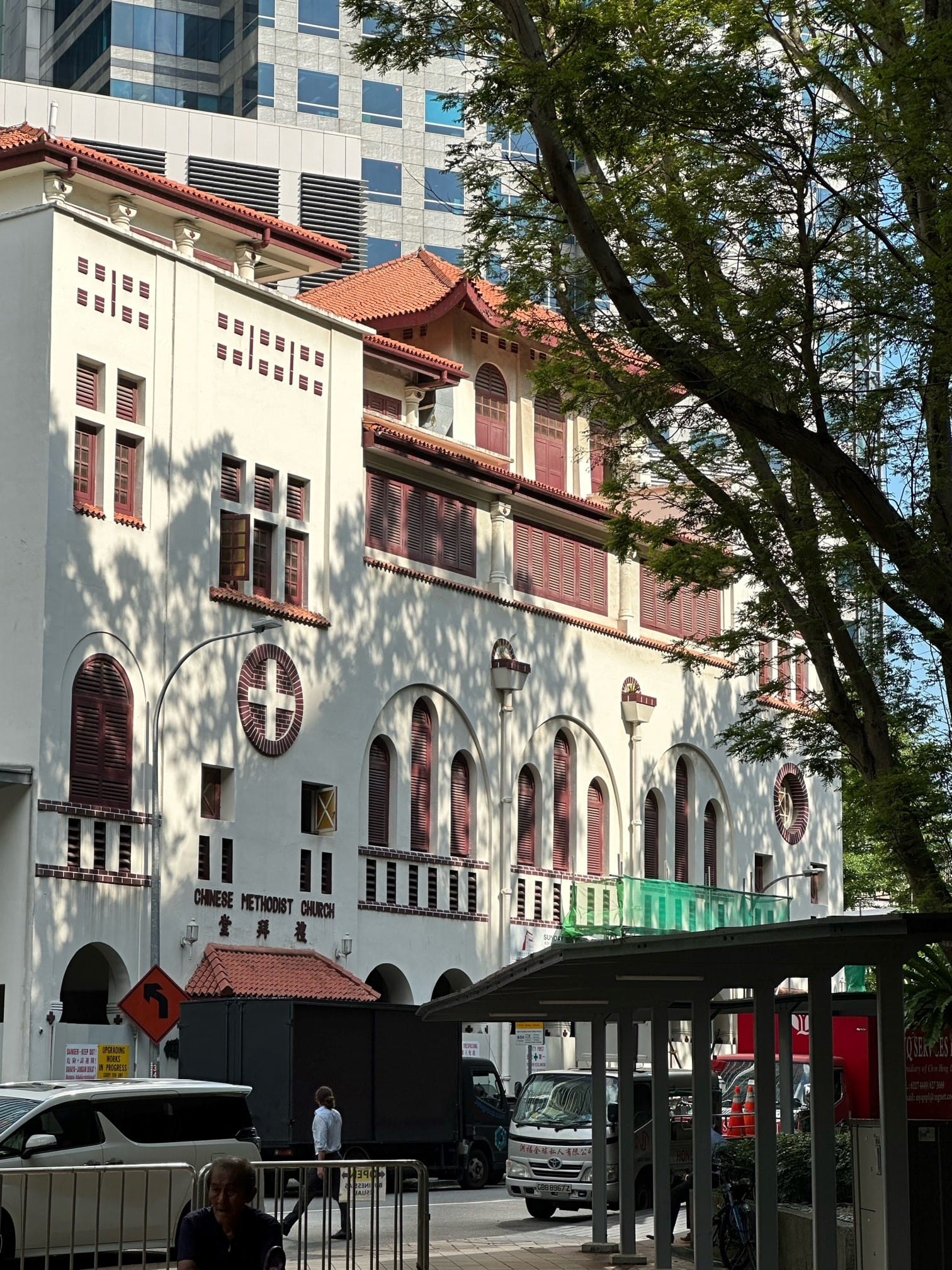 White colonial-style Chinese Methodist Church with red tile roof and arched windows, flanked by a modern glass tower.